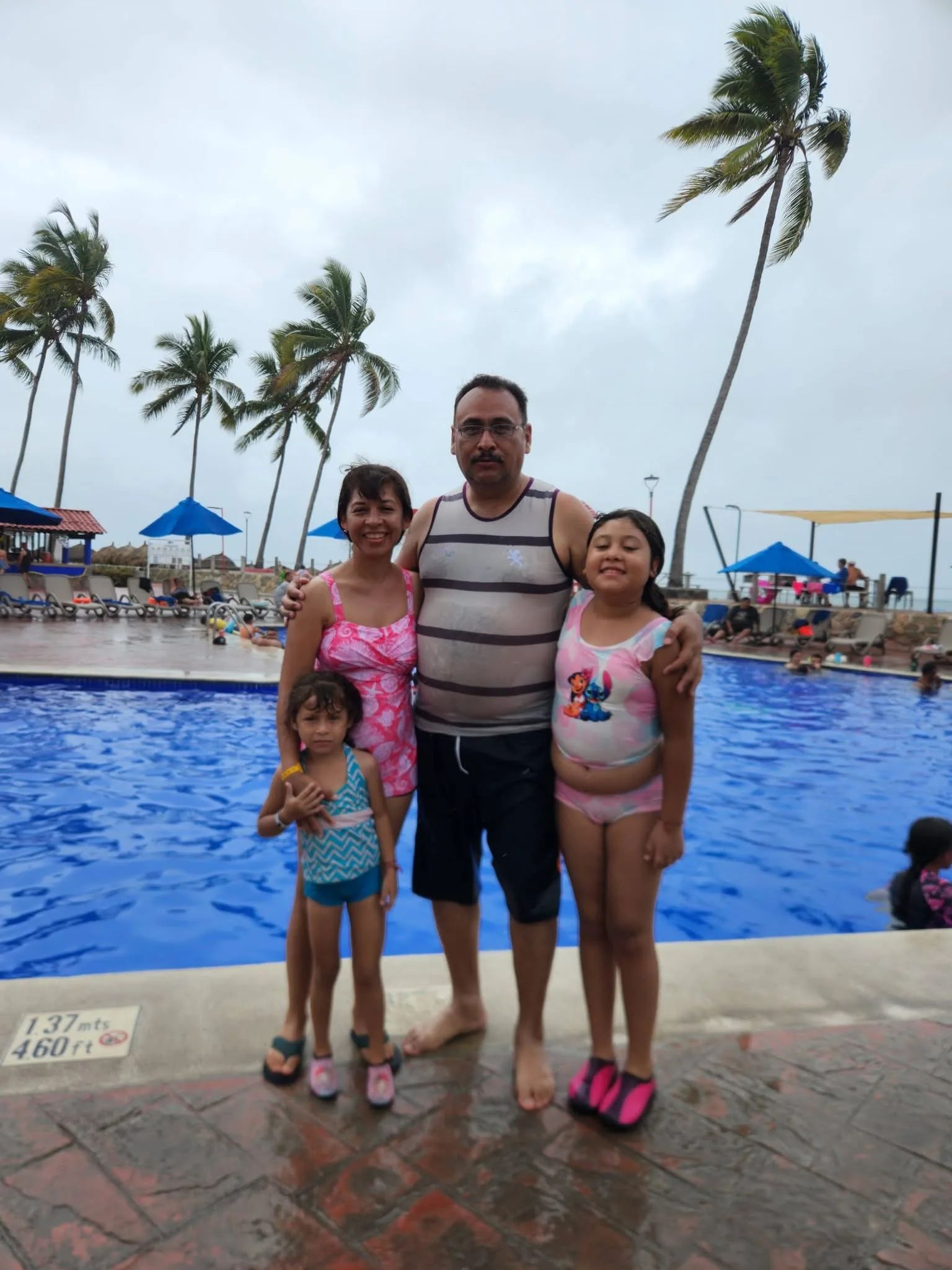 Familia en alberca con palmeras